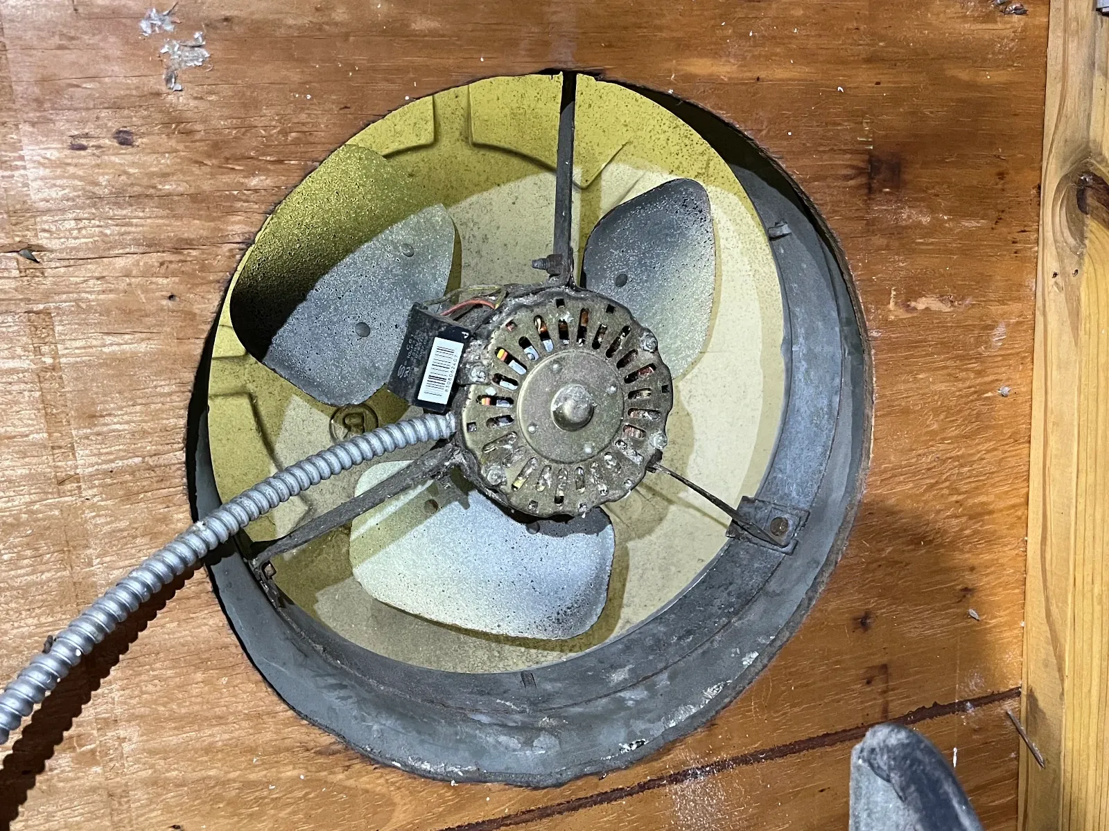 Original builder-grade gable attic fan with a seized motor, no longer spinning